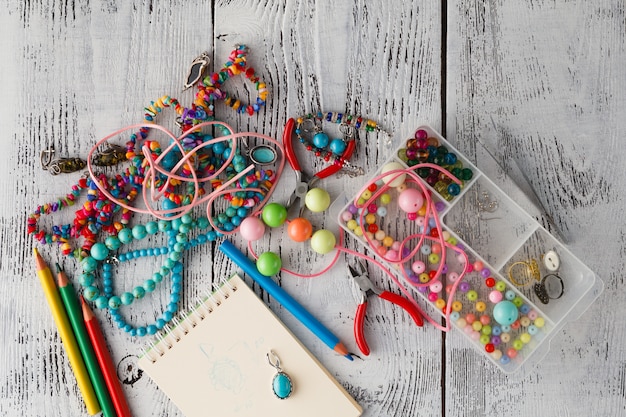 A close-up shot of a variety of craft supplies - colorful yarns, beads, fabrics - neatly organized, with a tablet in the background displaying a price comparison website for craft materials.