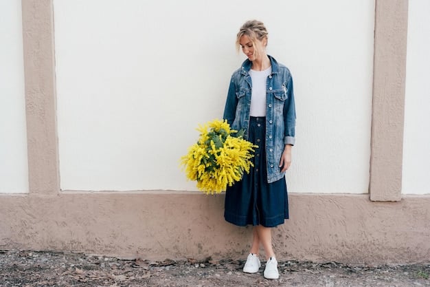 A fashion blogger showcasing a spring outfit. She is wearing a flowy midi dress with a floral print, paired with white sneakers and a denim jacket. The setting is a park with blooming flowers.