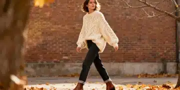 Stylish woman in cream chunky knit sweater, dark jeans, and ankle boots for a cozy and fashionable look.